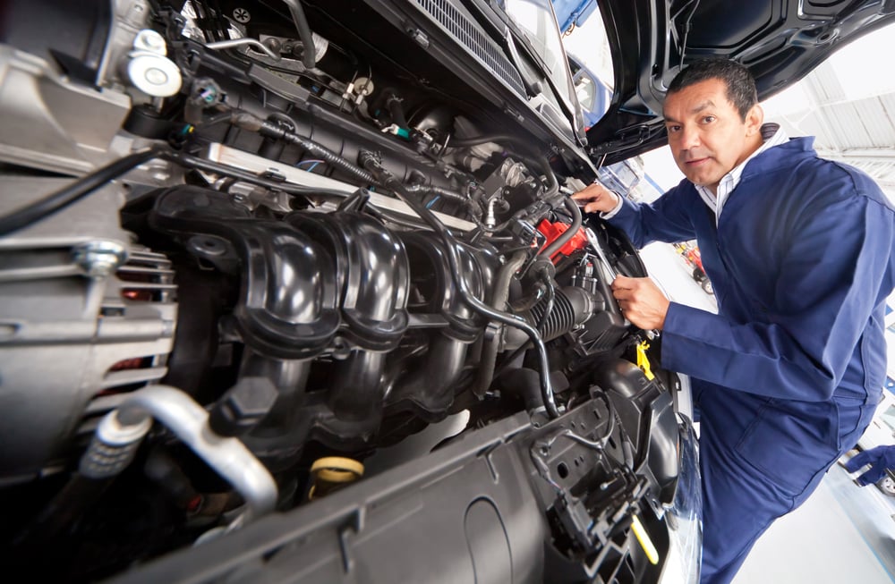 Car mechanic at the garage fixing the engine Car mechanic at the garage fixing the engine