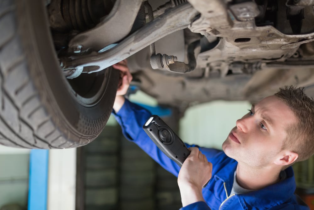 Male mechanic with flashlight examining tire Male mechanic with flashlight examining tire