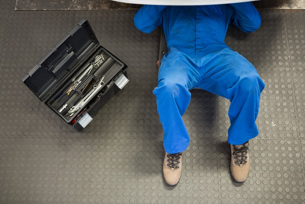 Mechanic lying and working under car at the repair garage Mechanic lying and working under car at the repair garage